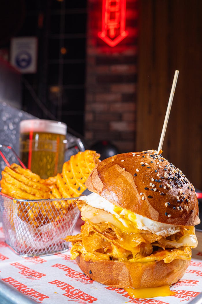 Delicious gourmet burger with toppings, served with waffle fries and cold beer in a cozy restaurant.